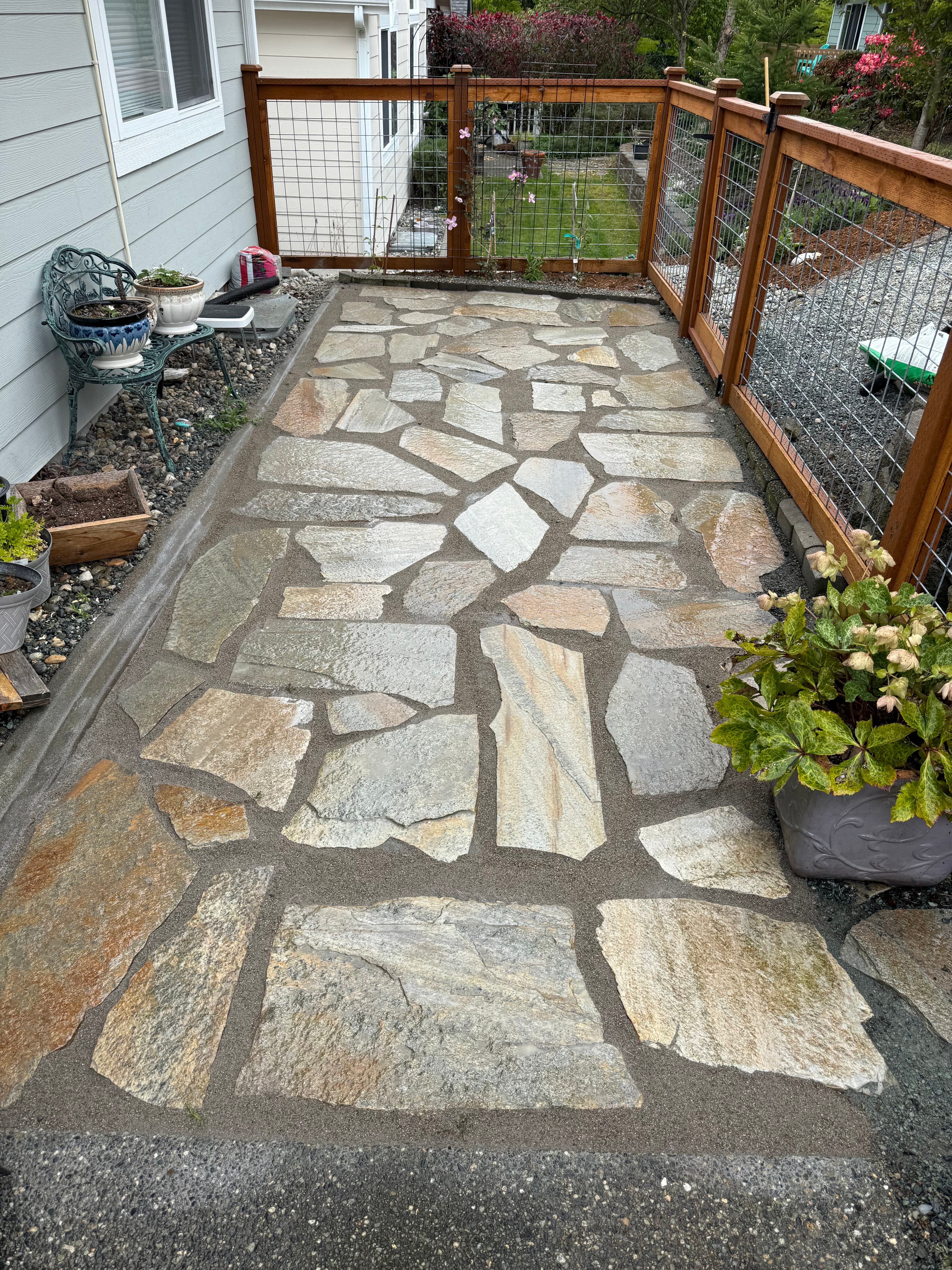 Daytime view of a WIL flagstone walkway beside a home and garden